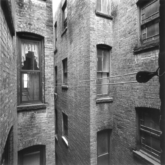 Existing light well space between the two, typical 1890's apartment buildings.  The stair core for each building has a wide double-hung window opening onto these.   Laundry line hardware pulley just outside the kitchen window from which this photo was taken before construction began.  Photo by David Bogle.